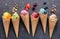 Various of ice cream flavor in cones blueberry ,strawberry ,pistachio ,almond ,orange and cherry setup on dark stone background .