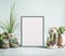 Various indoor plants and cactus in pots around blank white frame mock up on modern desktop background. Succulent plants concept.