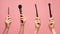 Various makeup brushes in female hands on pink background, closeup. Collage. Panorama