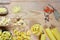 Various mix of pasta on wooden rustic background, wooden spoons, spices red pepper, bay leaf, diet and food concept, top view, wit