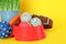 Various pet toys, bowl and wheatgrass on yellow background, closeup