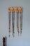 Various rosaries hanging on coat rack over light blue