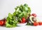 Various salad ingredients: green lettuce leaves, avocado, tomato, pomegranate seeds and strawberries on table at white wall