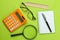 Various school supplies calculator, glasses, notebook on a bright green background. back to school. Office tools. education. top v