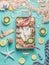 Various seafood in tray on light blue background with fishnet , seaweed and ingredients, top view