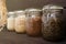 Various seeds in storage jars in pantry, dark wooden background. Smart kitchen organization