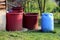 Various size shape and colors plastic barrels used for storing rainwater to be used with garden drip irrigation system