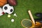 Various sport balls, baseball bat and glove, badminton racket on green lawn