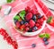 Various summer fruits in a bowl. Assorted fresh berries with lea