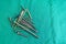 Various surgical titanium screws lie spread out on a green surgical drape