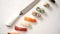 Various sushi rolls with Japanese knife on white stone slate background