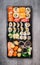 Various Sushi selection in black packaging tray on gray stone background, top view.
