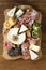 Various types of cheeses, grapes, walnuts and honey and prosciutto. Wooden cutting board