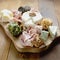 Various types of cheeses, grapes, walnuts and honey and prosciutto. Wooden cutting board