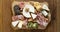 Various types of cheeses, grapes, walnuts and honey and prosciutto. Wooden cutting board