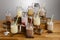 Various types of colouful milkshake and ingredients shaker and tape measure in Mason Jar glasses with paper straws on a wooden