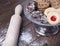 Various types of tasty cookies on glass tray next to a roller on wooden table.