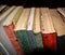 Various vintage dusty old books arranged on a shelf. Selective focus effect applied