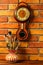 Vase with artistic brushes and old wooden wall clock with barometer and thermometer on the brick wall background