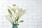 Vase of beautiful lilies against white brick wall