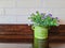 Vase with beautiful purple bouquets on blurred brick wall background