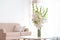 Vase with beautiful white gladiolus flowers on wooden table in living room