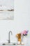 vase with colored flowers cups and wooden utensil on kitchen counter