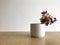 Vase with flowers on wooden table and white wall background.