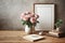 A vase pink roses sits on wooden table next to a framed white picture