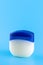 Vaseline or petroleum jelly in a clear jar on blue background with copy space for text. Skin care ointment