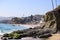 Vast blue ocean water crashing into the rocks along the beach with homes along the coastline with lush green palm trees