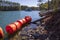 vast blue rippling water at Lake Lanier with large orange buoys in the water and lush green trees with rocks along the banks