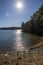 vast blue rippling water at Lake Lanier with the sun reflecting off the water and lush green trees with rocks along the banks