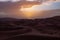 Vast desert landscape adorned with sandy dunes and a captivating sunset