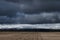 Vast fields, woods in the background, stormy weather