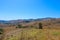 Vast open mountain range landscape covered with dry brush and green trees with blue sky at Chino Hills State Park
