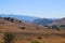 Vast open mountain range landscape covered with dry brush and green trees with blue sky at Chino Hills State Park
