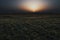 Vast rural grassy field under a glowing orange sunset sky