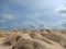 A vast wavy desert under bright blue sky with some clouds