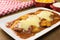 Veal parmigiana in a white platter with rice in and french fries in wood background close