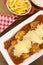 Veal parmigiana in a white platter with rice in and french fries in wood background seen from above vertical