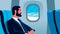 Vector flat illustration of a businessman on the plane looking out the window. Bearded man in suit on business trip by first class
