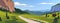 Vector flat summer landscape illustration, wild nature view: sky, mountains, meadow, road, village.