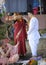 Vedic wedding. Bride and groom in wedding dresses standing on the ground during the marriage ceremony, bride putting the flower
