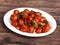 Veg Manchurian, Popular indo-chinese food made of cauliflower florets and other vegetable, served in a white plate over a rustic