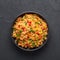 Veg Schezwan Fried Rice in black bowl at dark slate background. indo-chinese cuisine dish