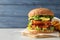 Vegan burger with carrot patties served on table against color background.