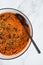 Vegan chilli sin carne with black beans and red lentils in spicy tomato sauce, healthy plant-based food