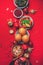 Vegan Christmas appetizers, olive, orange, fruits, vegetable salads, candles, tangerine, pomegranate, star glitter sparkles on red