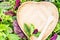 Vegan concept or diet with text space green salad leaves background and heart shaped plate.